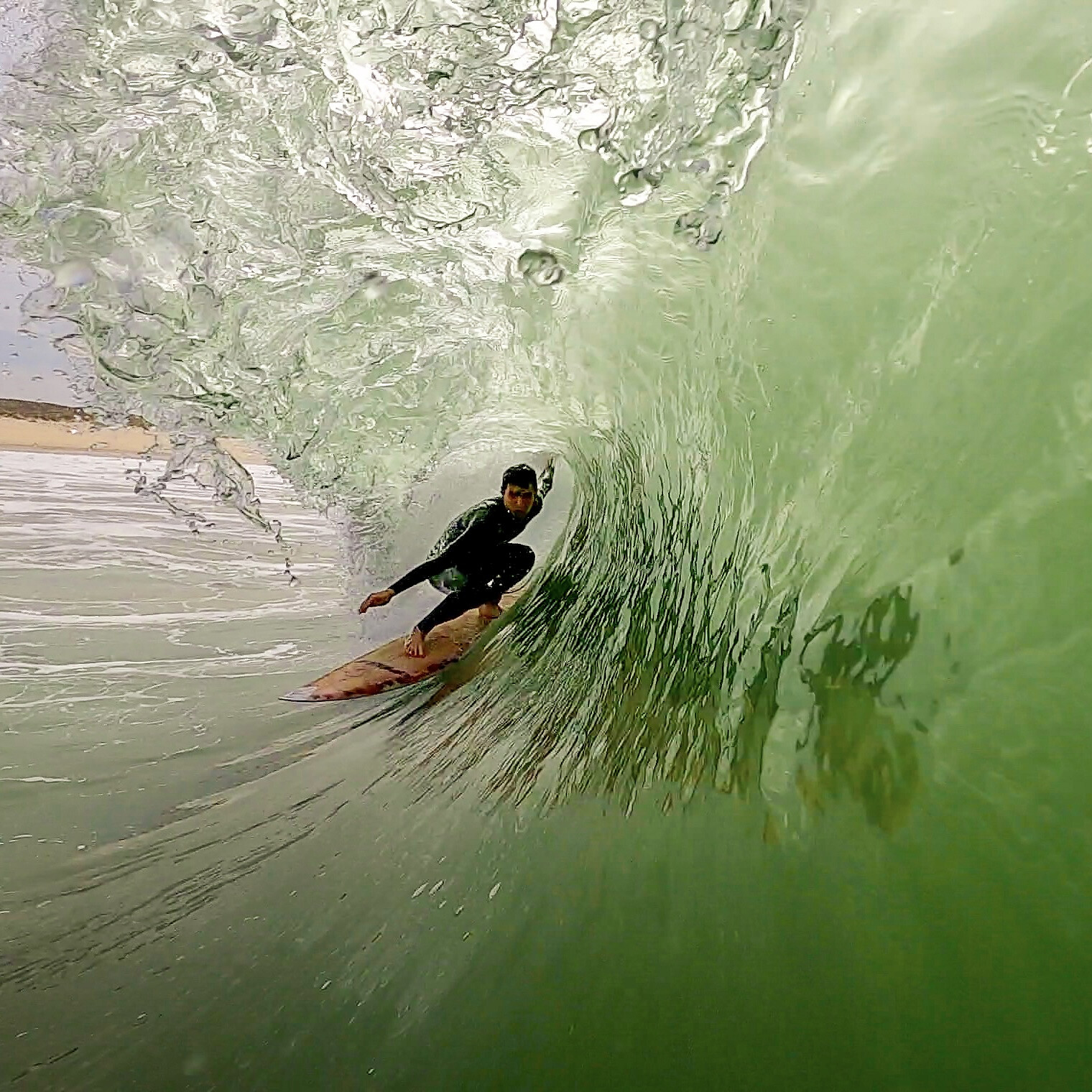Surfer inside a barrel, filmed from the water near Peniche